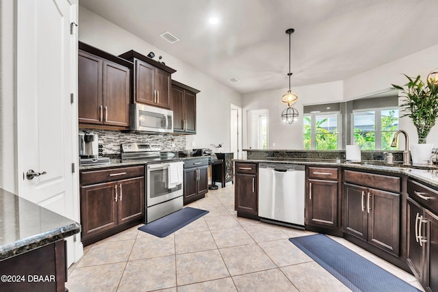 kitchen with appliances with stainless steel finishes, dark brown cabinetry, light tile patterned floors, hanging light fixtures, and sink