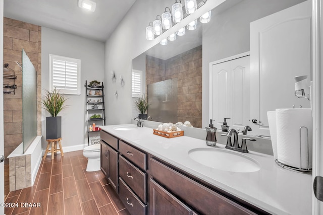 bathroom featuring toilet, vanity, and tiled shower