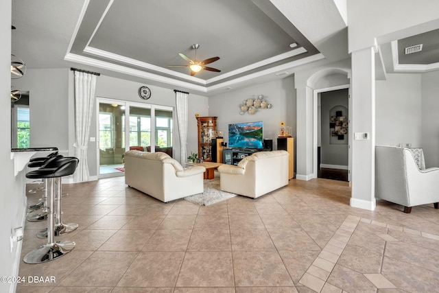 tiled living room featuring a tray ceiling and ceiling fan