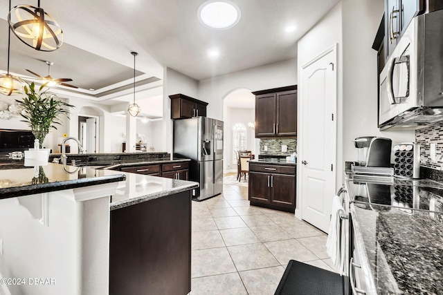 kitchen featuring appliances with stainless steel finishes, hanging light fixtures, sink, and dark stone counters