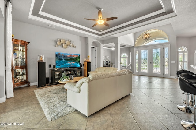 living room featuring a textured ceiling, ceiling fan, and a raised ceiling