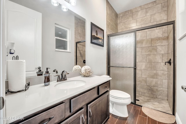 bathroom featuring toilet, wood-type flooring, vanity, and a shower with door