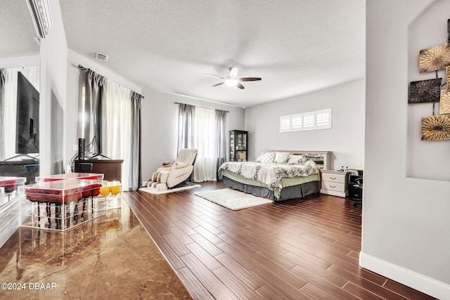 bedroom featuring dark wood-type flooring, ceiling fan, and a textured ceiling