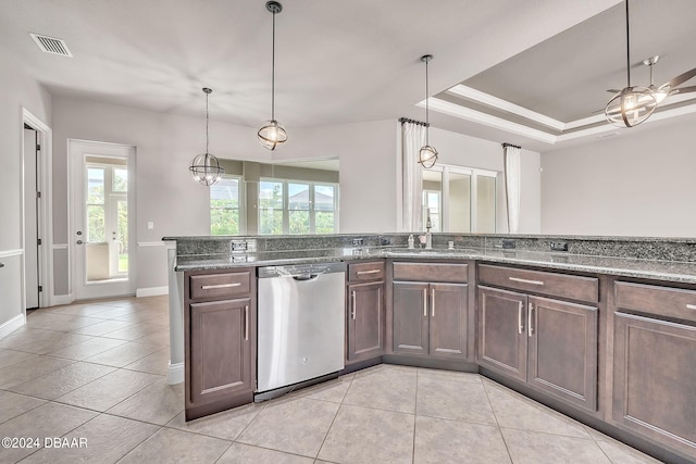 kitchen with sink, dark stone counters, light tile patterned floors, stainless steel dishwasher, and pendant lighting