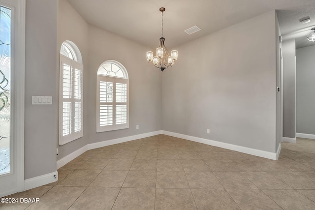 tiled spare room with a notable chandelier