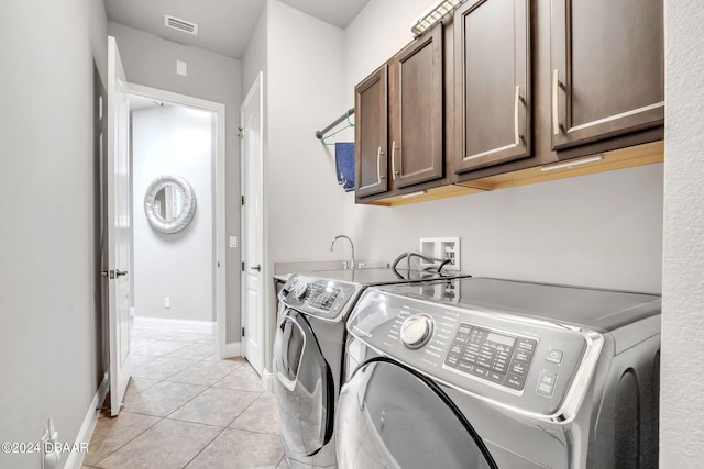 clothes washing area featuring cabinets, sink, washer and dryer, and light tile patterned floors