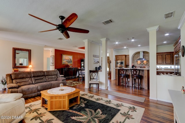 living room featuring ornamental molding, decorative columns, ceiling fan, and dark hardwood / wood-style floors