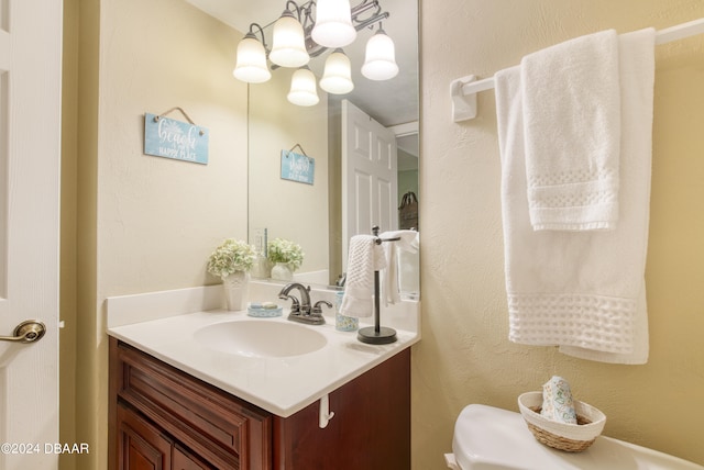 bathroom with a chandelier, vanity, and toilet