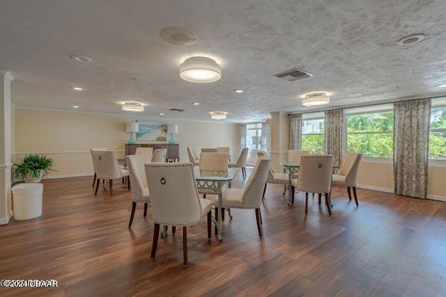 dining area with dark hardwood / wood-style flooring, a textured ceiling, and crown molding