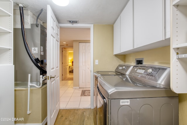 laundry room featuring light hardwood / wood-style floors, cabinets, and washer and dryer