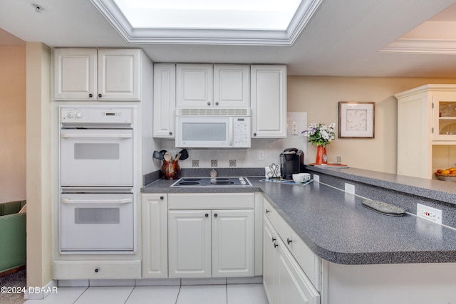 kitchen with kitchen peninsula, white appliances, light tile patterned flooring, and white cabinets