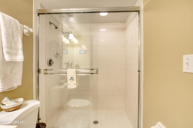 bathroom with a shower with door and toilet