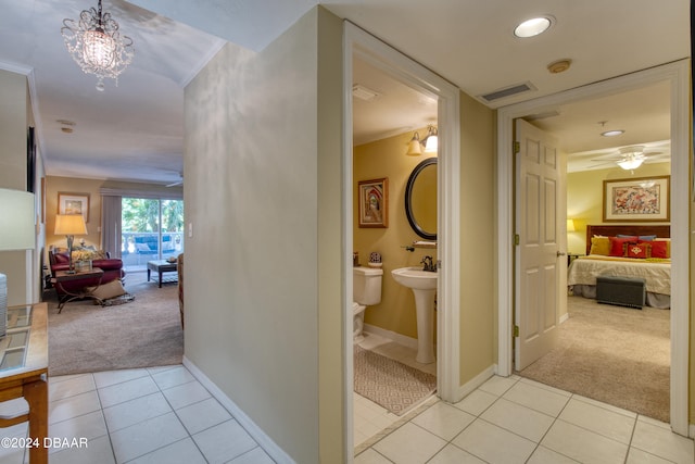 corridor with light tile patterned flooring, sink, an inviting chandelier, and ornamental molding