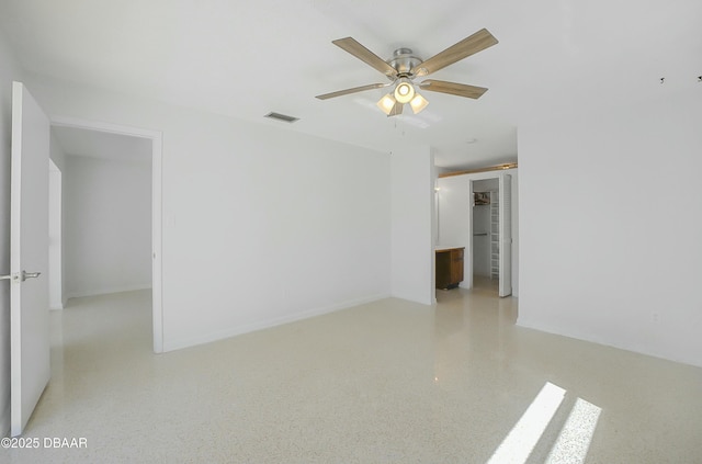 spare room featuring visible vents, baseboards, speckled floor, and ceiling fan