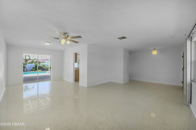 spare room featuring visible vents, light speckled floor, baseboards, and a ceiling fan