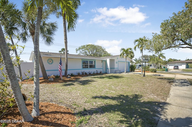 single story home featuring stucco siding, driveway, a front yard, and a garage