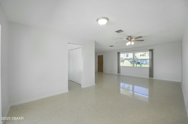 spare room with visible vents, a ceiling fan, a textured ceiling, speckled floor, and baseboards