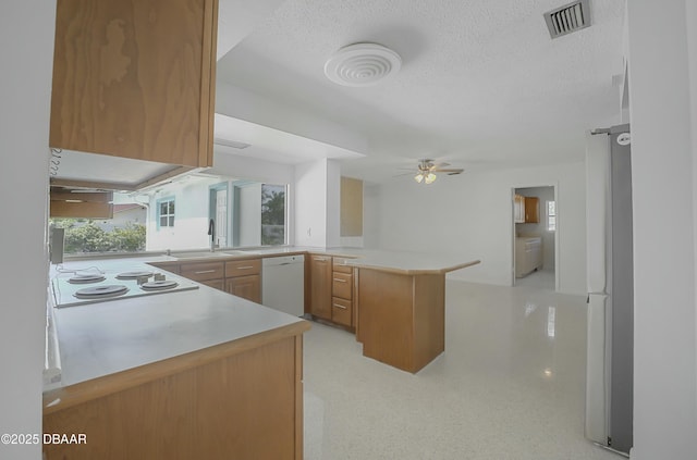 kitchen featuring white appliances, a peninsula, a sink, light countertops, and a textured ceiling