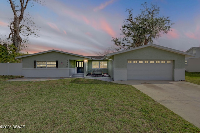 single story home featuring a garage and a lawn