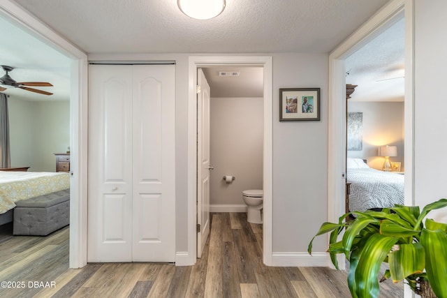 325 N Causeway Cswy Unit B305, New Smyrna Beach, FL 32169 - bathroom featuring ensuite bathroom, wood finished floors, a ceiling fan, a closet, and a textured ceiling