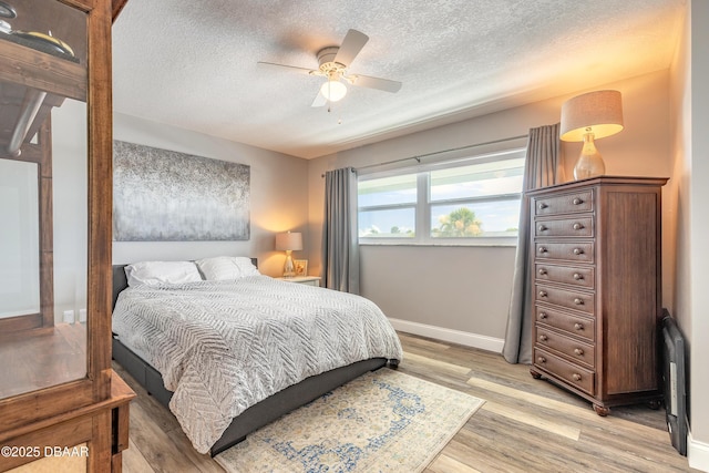 325 N Causeway Cswy Unit B305, New Smyrna Beach, FL 32169 - bedroom featuring a textured ceiling, light wood-type flooring, a ceiling fan, and radiator heating unit