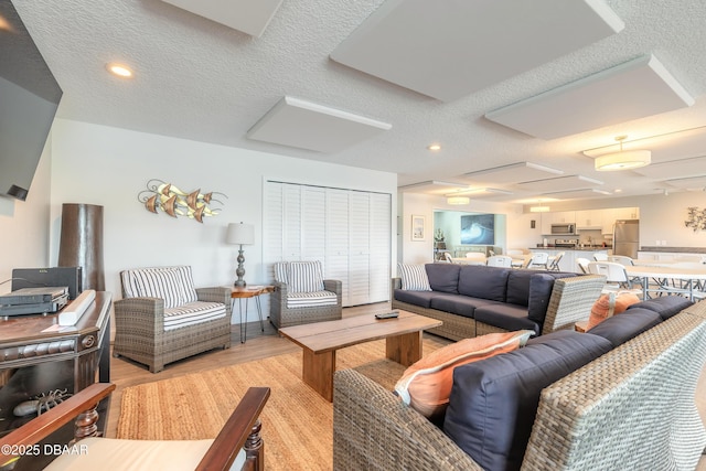 325 N Causeway Cswy Unit B305, New Smyrna Beach, FL 32169 - living room with light wood-style flooring, a textured ceiling, and recessed lighting