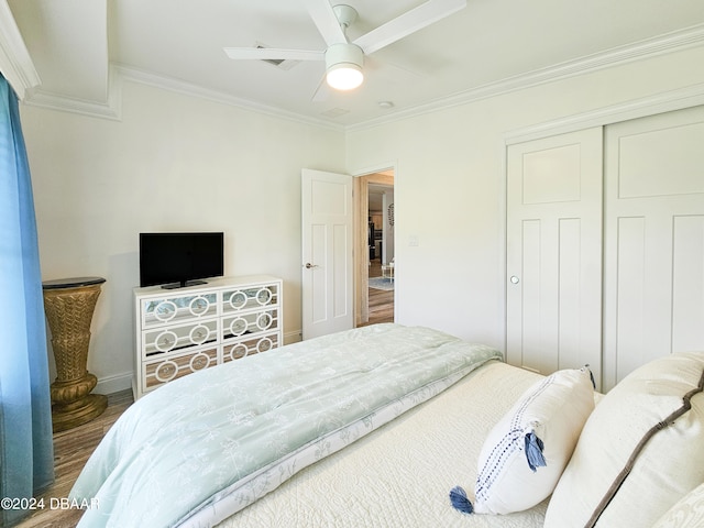 bedroom featuring ornamental molding, a closet, ceiling fan, and dark hardwood / wood-style floors