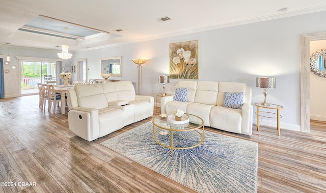 living room with ornamental molding, hardwood / wood-style flooring, and a tray ceiling