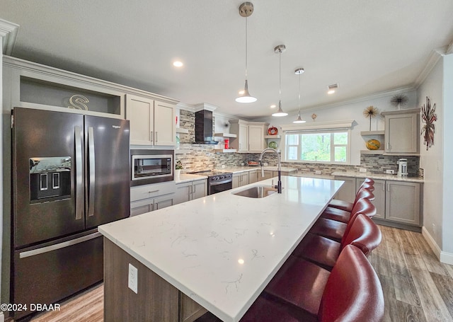 kitchen featuring stainless steel appliances, sink, a kitchen island with sink, and decorative light fixtures