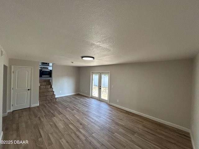 unfurnished living room with hardwood / wood-style flooring, a textured ceiling, and french doors