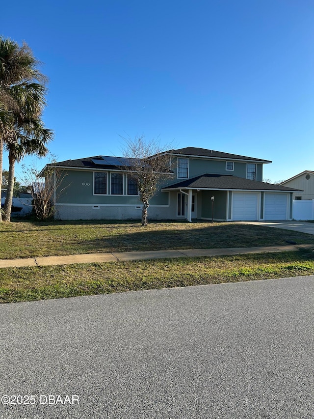 view of front of property featuring a garage, a front yard, and solar panels