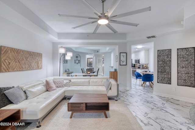 living room with ceiling fan and a raised ceiling