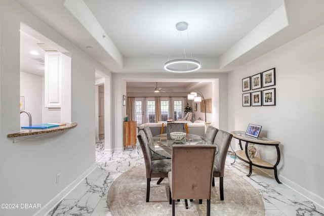 dining space featuring french doors, a tray ceiling, and ceiling fan