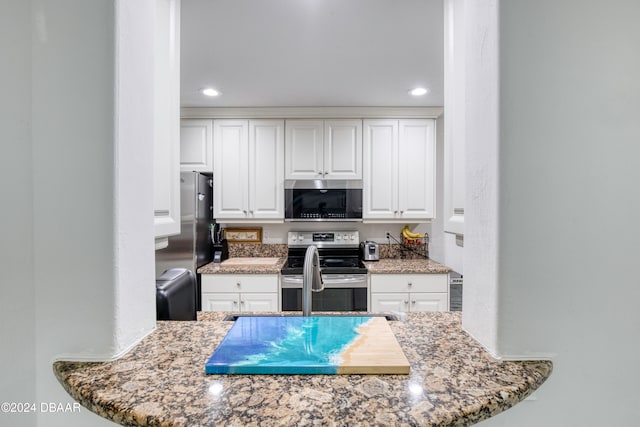 kitchen with white cabinets, stainless steel appliances, and stone countertops