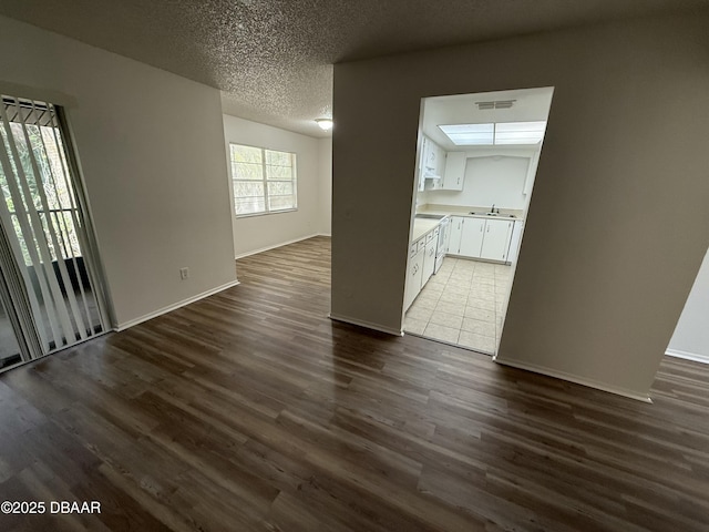 interior space with dark wood finished floors, baseboards, a textured ceiling, and visible vents
