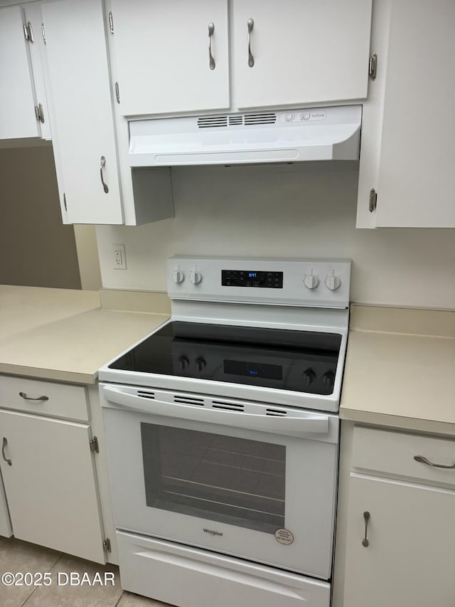 kitchen with white electric range oven, tile patterned floors, white cabinetry, light countertops, and under cabinet range hood