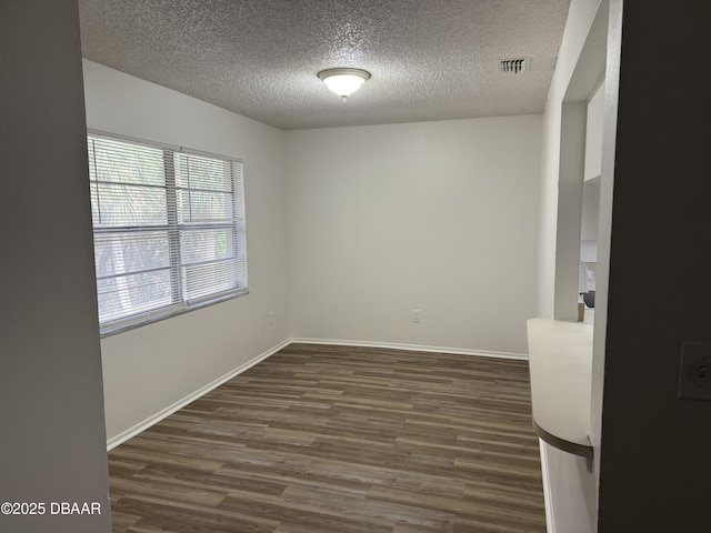 empty room featuring baseboards, visible vents, a textured ceiling, and dark wood-style flooring