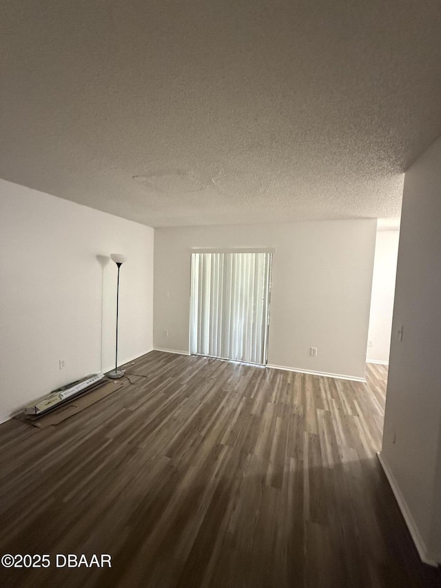 unfurnished room with baseboards, wood finished floors, and a textured ceiling