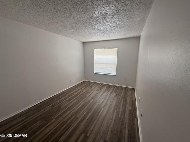 empty room with baseboards, a textured ceiling, and dark wood-type flooring