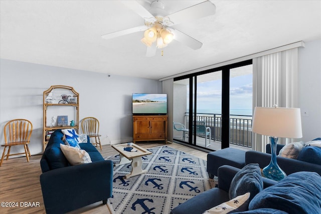 living room with ceiling fan, expansive windows, and wood-type flooring