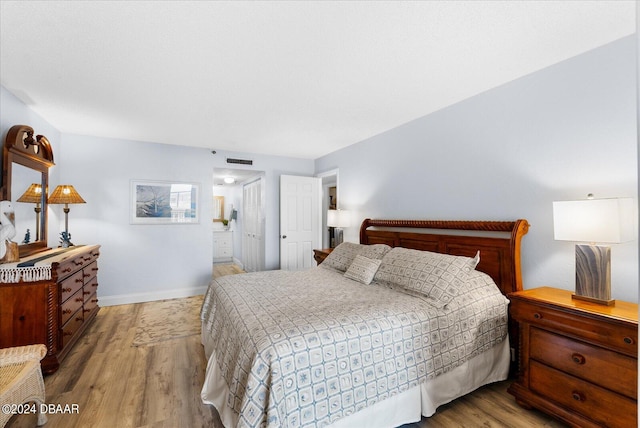 bedroom with light wood-type flooring and connected bathroom