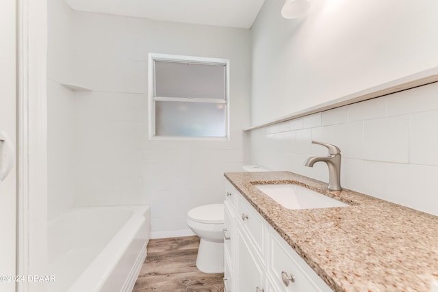 bathroom featuring hardwood / wood-style floors, vanity, toilet, and tile walls