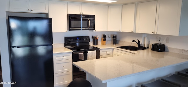 kitchen with kitchen peninsula, sink, a breakfast bar, and black appliances