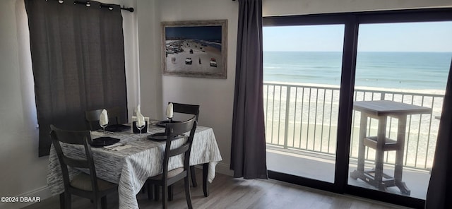 dining room featuring light hardwood / wood-style flooring, a water view, and a beach view