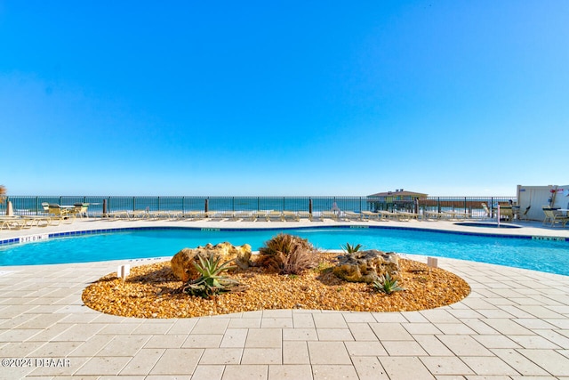 view of pool featuring a water view and a patio