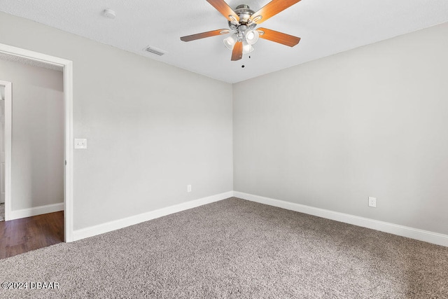 empty room with ceiling fan and dark carpet