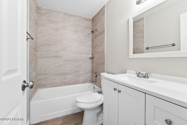 full bathroom with wood-type flooring, vanity, a textured ceiling, toilet, and tiled shower / bath