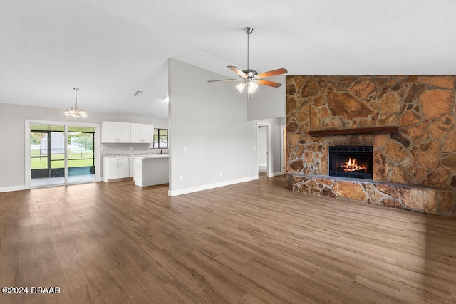 unfurnished living room featuring high vaulted ceiling, wood-type flooring, ceiling fan with notable chandelier, and a fireplace