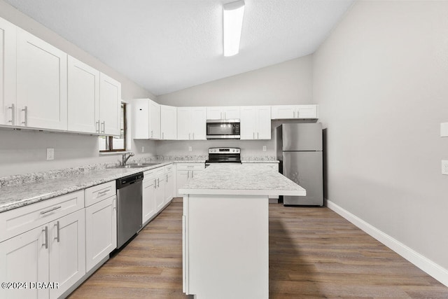 kitchen featuring white cabinetry, appliances with stainless steel finishes, vaulted ceiling, dark wood-type flooring, and a center island