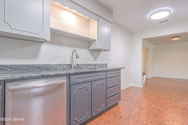 kitchen with sink, dark stone counters, stainless steel dishwasher, gray cabinetry, and dark hardwood / wood-style flooring